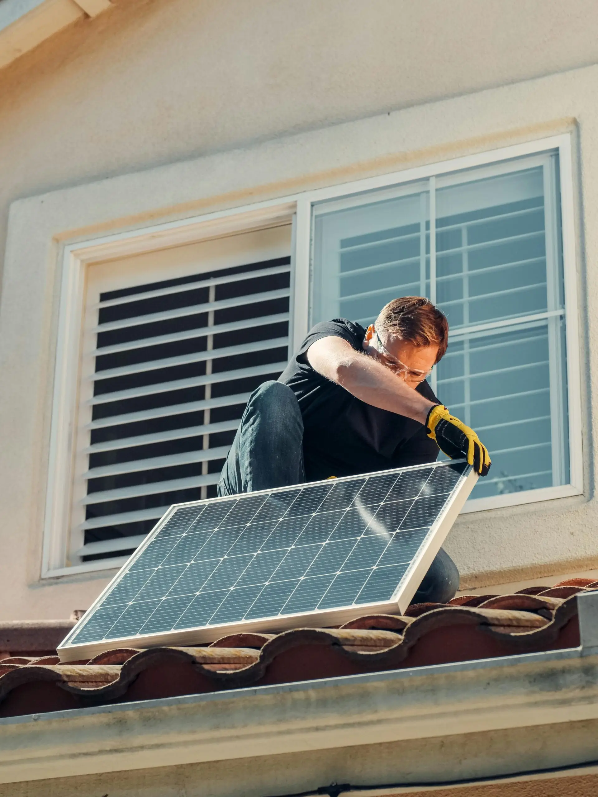 Solar installer positioning a panel on a tiled roof